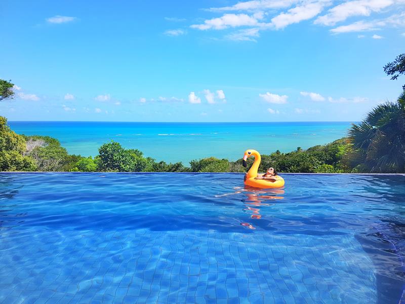 piscina de borda infinita e muito verde na pousada do alto